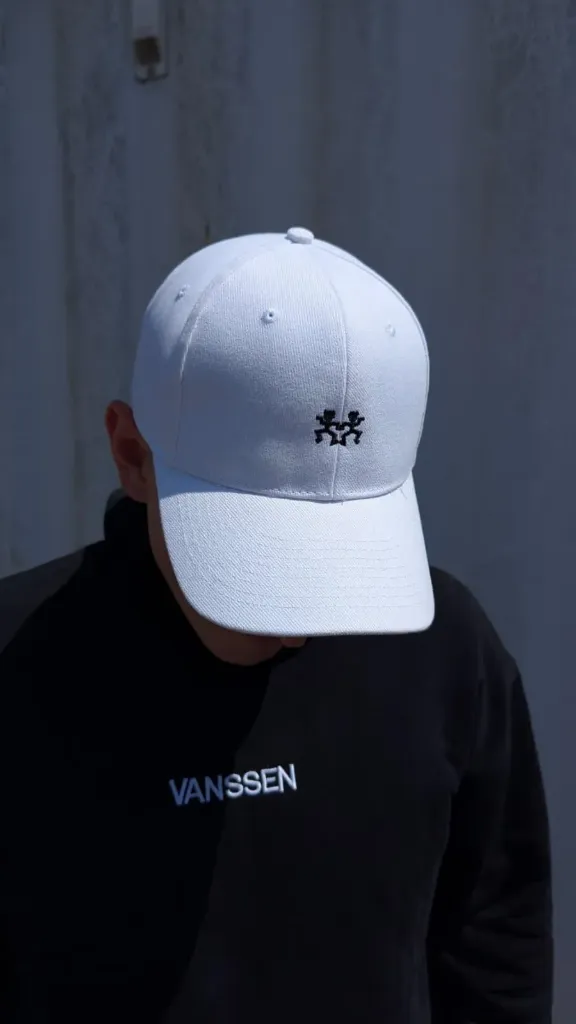 Casquette blanche et pull noir.webp